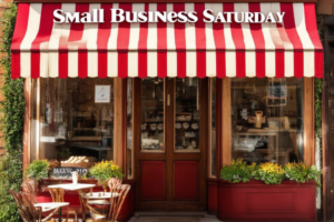 Vintage-style bakery shopfront with a sign promoting Small Business Saturday and Legacy Builder opportunities through DailyPay4All.com